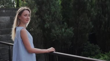 Güzel kız sokakta, bahçede dikiliyor.