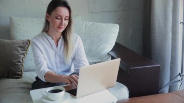 Kanepede dizüstü bilgisayarla çalışan güzel bir kız.