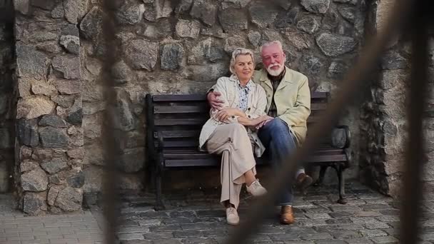 Uomo con donna seduta sulla panchina davanti al muro di pietra — Video Stock