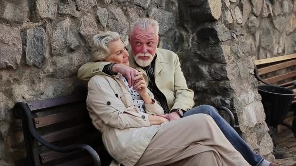 Mann und Frau sitzen auf Bank vor Steinmauer — Stockvideo