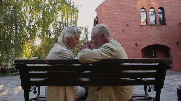 Старша жінка сидить на лавці тягне на чоловічий ніс — стокове відео