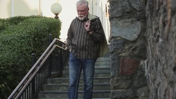 Homme tenant une veste sur l'épaule par un escalier — Video