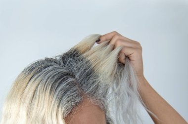 Mujer raiz pelo con canas tinte cabello rubio mostrar raves fondo claro una mano