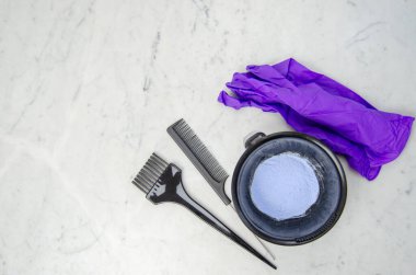 Utensilios de peluquera para decoloracin tinte pelo en polvo azul con guantes pee y brocha sobre fondo marmolado.