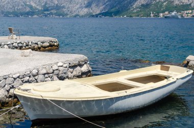 Beyaz tekne, arka planda mavi bir denizle limana demirlemiş.