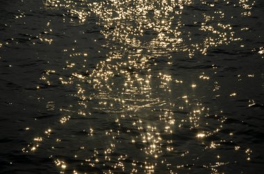 Gün batımında ışıldayan deniz yüzeyi arka plan olarak uygun.