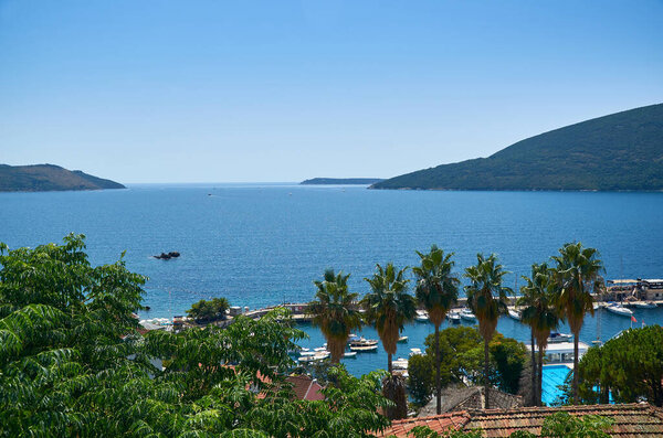 Impressive view to a bay with palms and lush mediterranean plants and roofs