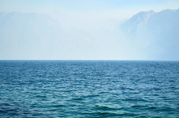 Morning mist over mountains and calm blue sea in summer