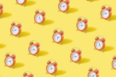 Pastel sarı arkaplanda bej rengi alarm saati motifi.