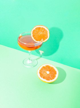 Kristal kokteyl bardağı ve taze klişeleşmiş greyfurtlu klasik retro sahnesi çift tonlu pastel yeşil arka plan.