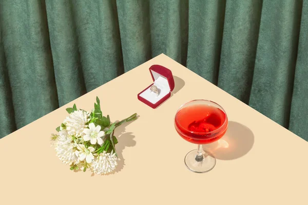 Retro vintage wedding party scene with red wine glass, bridal bouquet and engagement ring box on bright sandy table and stylish green plush curtain. Creative copy space. Isometric view.