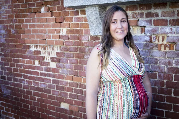 七个月的孕妇穿着五颜六色的条纹连衣裙站在户外 白天的场景 — 图库照片