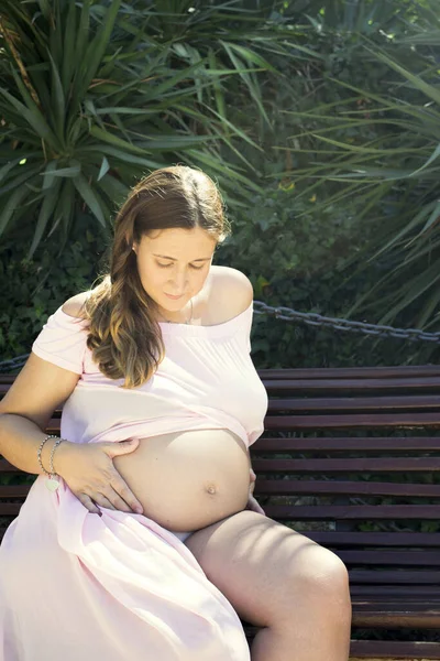 七个月的孕妇坐在木制长椅上非常快乐的表情 — 图库照片