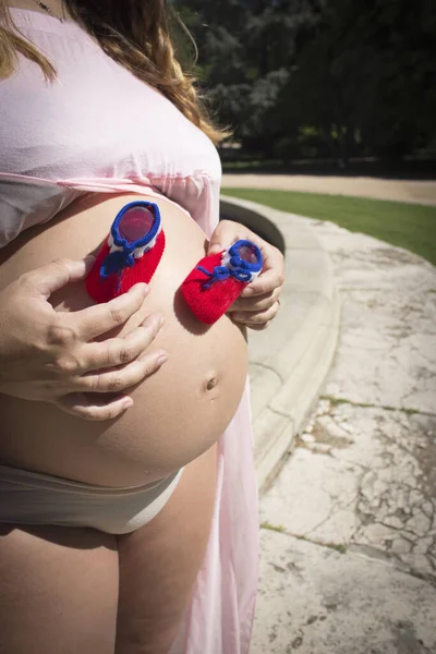 七个月的孕妇 肚子上长着红色和蓝色的靴子 — 图库照片