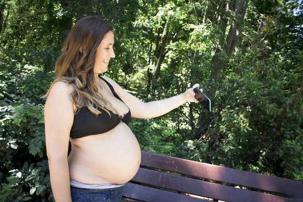 七个月的孕妇在公园里自拍 — 图库照片