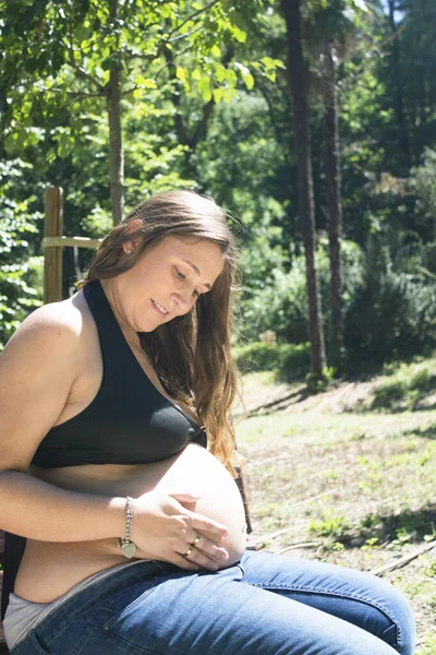 七个月的孕妇穿着牛仔裤在公园里 — 图库照片