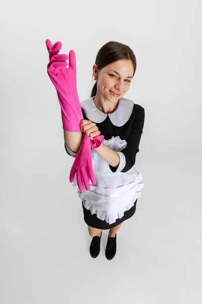 Portret młodej pięknej białej kobiety zakładającej różowe gumowe rękawiczki do czyszczenia na białym tle — Zdjęcie stockowe