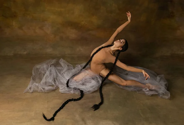 Retrato horizontal de larga duración de la suave bailarina en tela beige que muestra movimientos suaves sobre fondo vintage — Foto de Stock