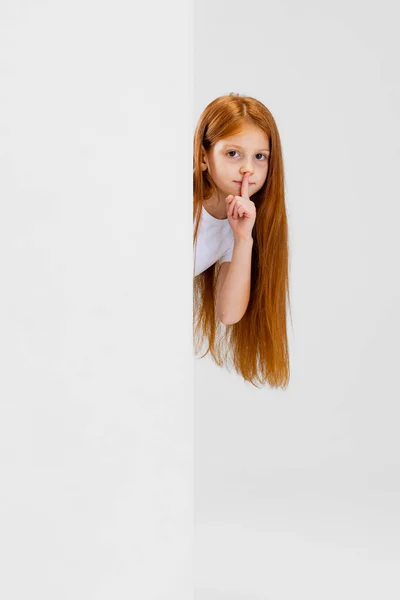 Vágott portré játékos kislány, tanuló néz ki a sarkon elszigetelt fehér háttér — Stock Fotó