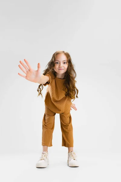 Retrato de cuerpo entero de una niña caucásica, posando para niños, saludando a la cámara aislada sobre un fondo gris de estudio —  Fotos de Stock