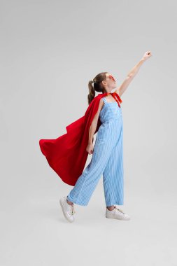 Beyaz stüdyo arka planında izole edilmiş küçük beyaz kızın portresi. Küçük süper kahraman.