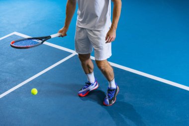 Üst görünümde, tenis raketi tutan erkek tenisçinin yarı görüntüsü ve arka planda izole edilmiş top tekmesi.