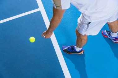 Erkek tenisçinin jimnastik arka planında izole edilmiş bir topa dönüşmeye hazırlanması.