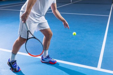 Üniformalı tenis oyuncusunun topa vurmaya hazır haldeki görüntüsü spor salonunun arka planında izole edilmiş.