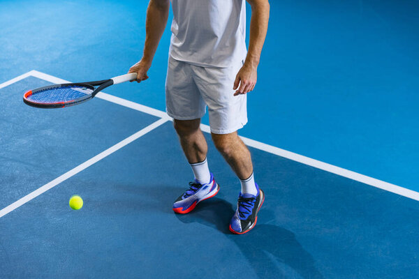 Вид сверху половина изображения теннисиста в движении держа теннисную ракетку и ногами мяч изолирован на фоне тренажерного зала