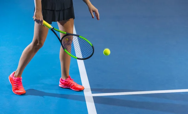 Image recadrée de joueuse de tennis en mouvement, jambes en chaussures de sport lumineuses isolées sur fond de court de tennis. Servir une balle — Photo