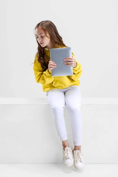 Portrait of little Caucasian girl, child with tablet isolated over white studio background. Watching cartoons — Stock Photo, Image