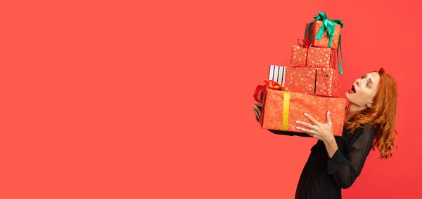Vágott portré gyönyörű vörös hajú nő kezében sok ajándék dobozok elszigetelt piros háttér. Üdülési bevásárlás. Szórólap — Stock Fotó
