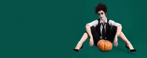 Portré művésznő jelmezt visel híres film karakter, ül tök elszigetelt zöld háttér. Halloweeni ötlet. Szórólap — Stock Fotó