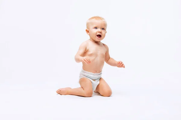 Retrato de niña linda, bebé en pañal arrodillado aislado sobre fondo blanco del estudio — Foto de Stock