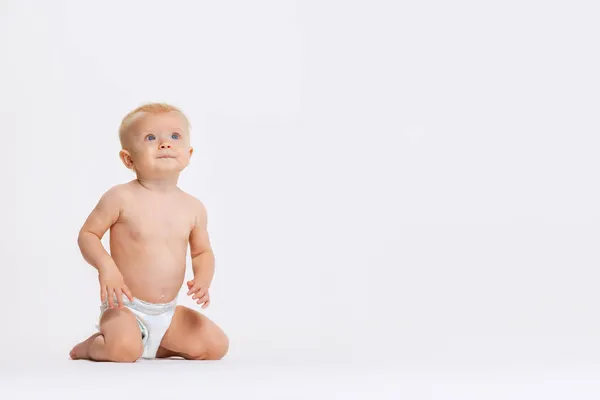 Retrato de cuerpo entero de una niñita linda, bebé sentado tranquilamente en pañal aislado sobre fondo blanco del estudio —  Fotos de Stock