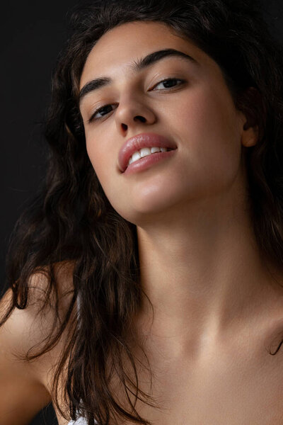 Обрезанный портрет красивой молодой женщины с естественным макияжем изолированы на темном фоне