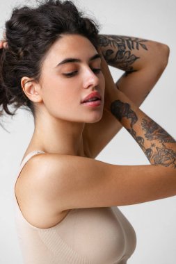 Doğal çıplak kadın portresi. Gri arka planda saç kaldırıyor.