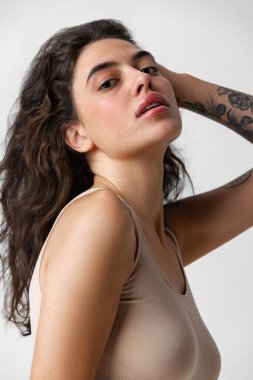 Doğal çıplak kadın portresi. Gri arka planda izole edilmiş kameraya bakıyor.