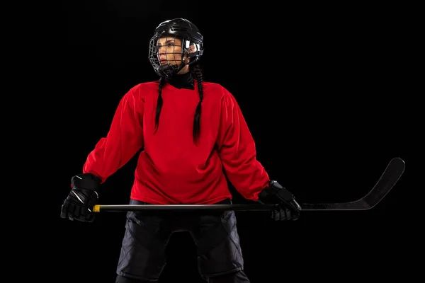 Cropped portrait of woman, professional hockey player in special protective uniform with helmet and hockey stick isolated over black background. — Stock Photo, Image