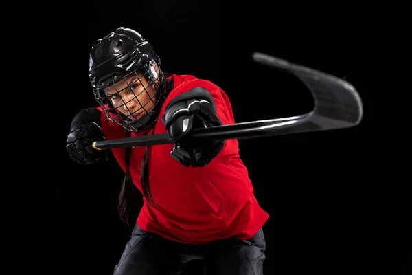 Cropped portrait of professional female hockey player training in special uniform with helmet isolated over black background. — Stock Photo, Image