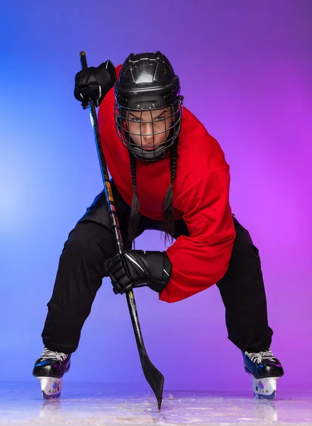 Full-length portrait of professional female hockey player, goalkeeper training isolated over gradient blue purple background.