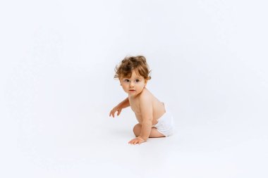 Güzel çocuk. Küçük tatlı bir çocuğun portresi, bebek bezi giymiş bebek beyaz stüdyo arka planına garip bir şekilde izole edilmiş bir şekilde bakıyor. Çocukluk kavramı, annelik, yaşam, doğum. İlan için alanı kopyala