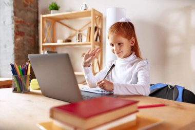Online dersler sırasında küçük bir kızın portresi, dizüstü bilgisayarla öğretmeni dinlemek, notlar almak. Ev çalışması