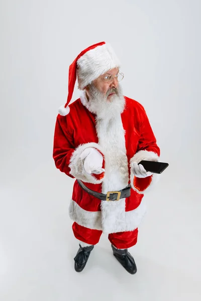 Retrato completo de homem idoso vestindo traje de Papai Noel, segurando telefone isolado sobre fundo branco. Notificação de férias — Fotografia de Stock