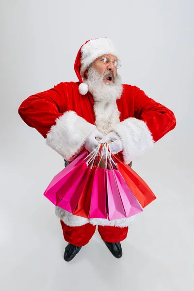 Retrato de cuerpo entero del hombre mayor con traje de Papá Noel, sosteniendo muchos paquetes de compras aislados sobre fondo blanco. Preparación para las vacaciones —  Fotos de Stock