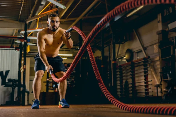 Портрет спортивного человека, делающего упражнения с веревкой. Развиваются мышцы. Спортивный зал — стоковое фото