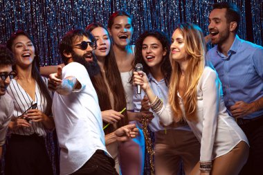 Karaokenin tadını çıkarıyorum. Bir grup genç kutlamada eğleniyor.