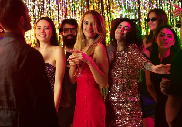 Neon ışıkları altında dans eden bir grup neşeli arkadaş. Yeni yıl, Noel kutlaması