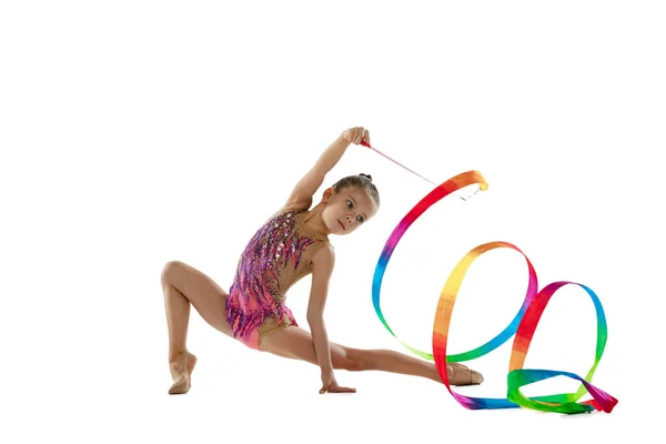 Full-length portret van klein meisje, professionele ritmische gymnastiek training, uitvoeren met kleurrijke lint geïsoleerd over witte achtergrond — Stockfoto