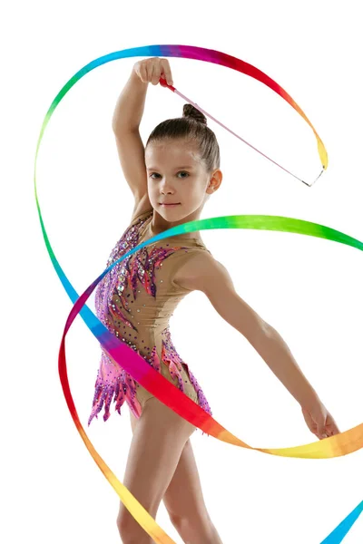 Ganztägiges Porträt eines kleinen Mädchens, professionelle rhythmische Turnausbildung, die mit buntem Band isoliert vor weißem Hintergrund auftritt — Stockfoto